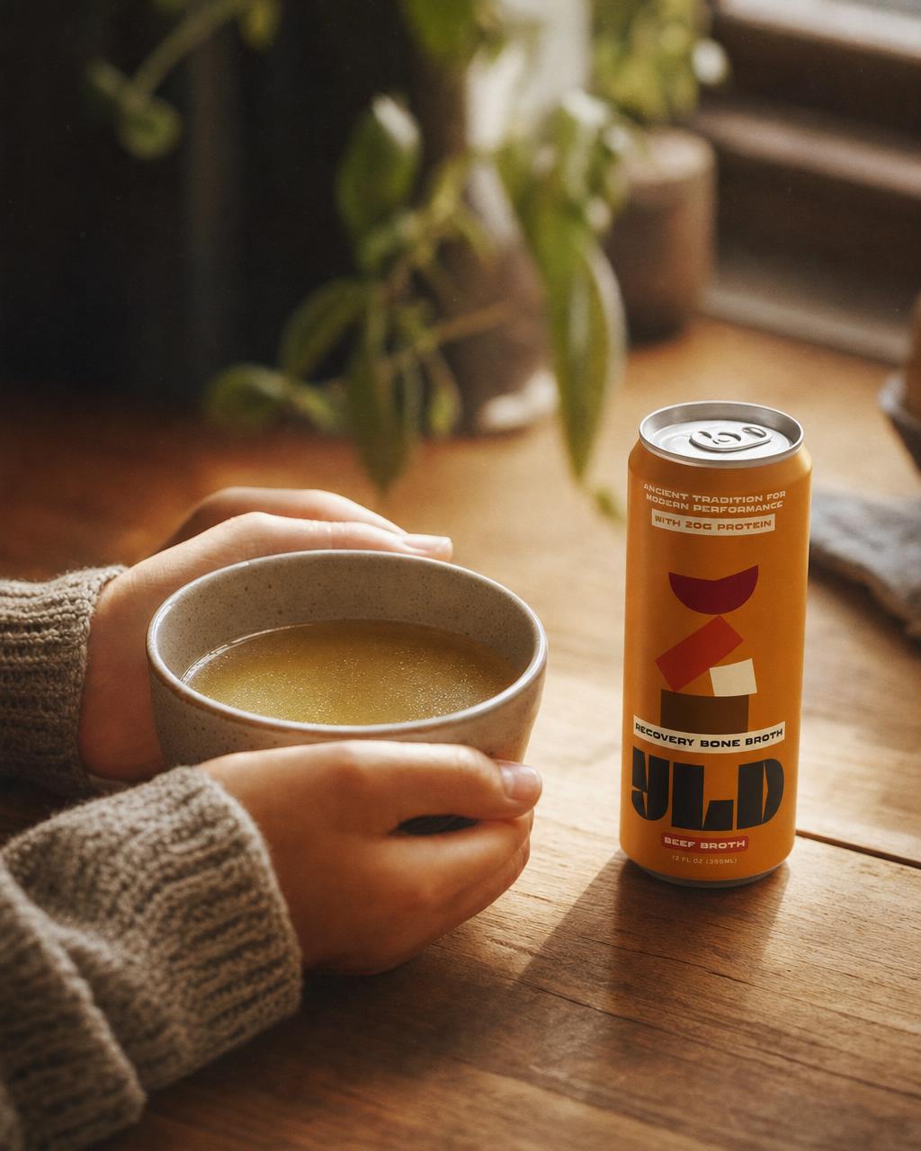 Hands cradling a warm cup of YLD broth by a sunlit window